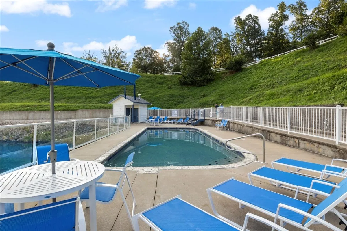 A sparkling outdoor swimming pool surrounded by blue umbrellas and lounge chairs, inviting guests to swim, sunbathe, and unwind. The pool area is set against a scenic backdrop, offering a welcoming space for families to cool off and socialize after a day of exploration.
