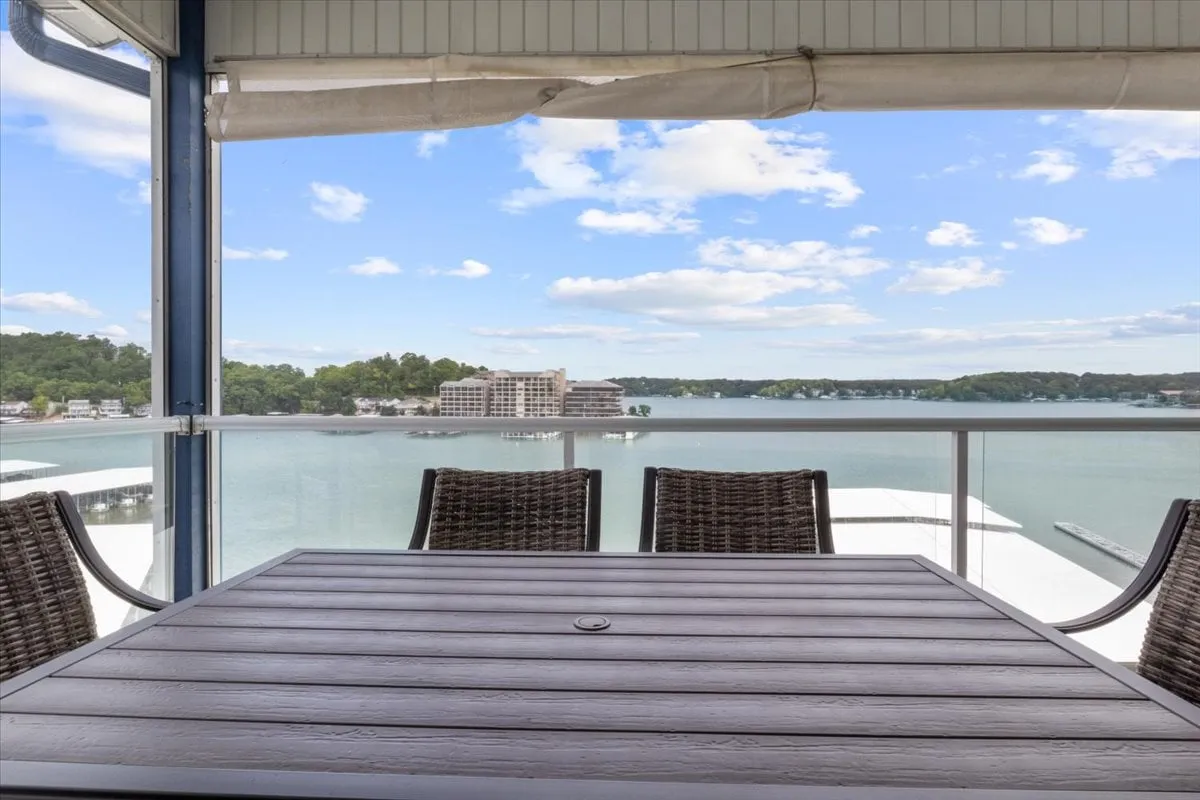 A serene balcony setting with a table and chairs positioned to overlook the expansive lake, sky, and tranquil water views. The outdoor dining area is inviting, suggesting it’s perfect for morning coffee, sunset toasts, or intimate meals while enjoying the beautiful lakefront scenery.