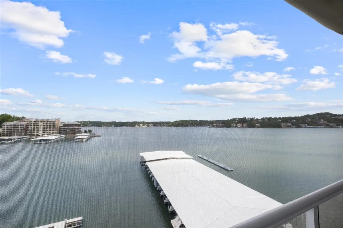 A stunning lakeside view featuring tranquil water, boat docks, and fluffy clouds drifting across the sky. The setting is ideal for boating, fishing, or simply relaxing by the water, with a vibrant yet serene atmosphere. The image captures the essence of lakeside adventure and relaxation, with the main channel clearly visible.