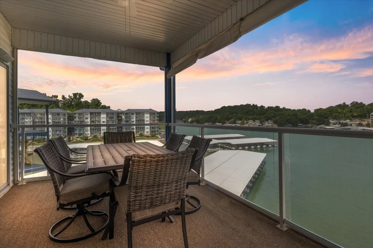 This image features an outdoor dining table set overlooking the lake, framed by a colorful sunset. The setting invites socializing, relaxing, and dining while immersed in the serene waterfront atmosphere.