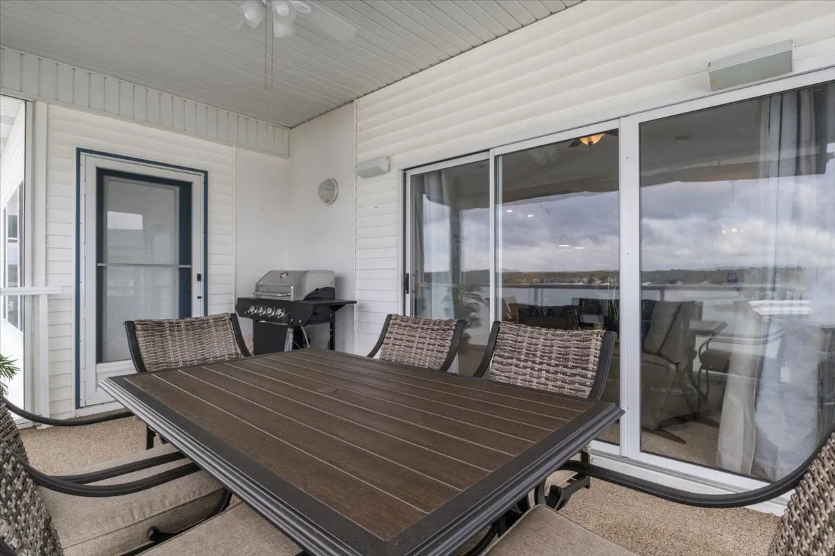 An exterior shot showing an outdoor dining table, grill, and large glass doors leading back into the condo. The setup is perfect for barbecuing, dining al fresco, and socializing with friends or family in a laid-back lakeside environment.