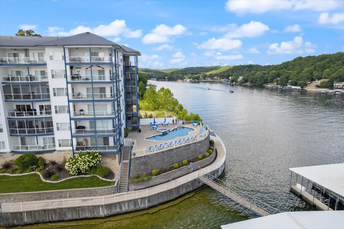 An inviting pool area overlooking the lake, with a waterfront view and balconies in the background. The peaceful pool setting offers space for relaxation, swimming, and enjoying the natural beauty of the lake, reinforcing the sense of resort-style amenities and leisure.